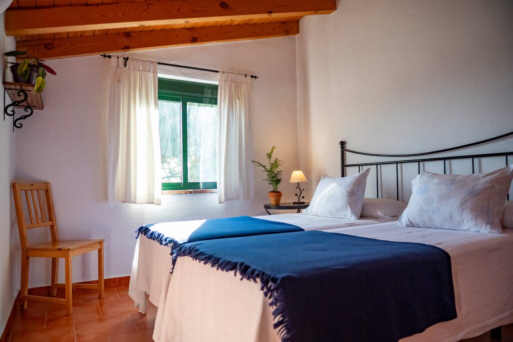 Dormitorio elegante en casa rural con textiles en tonos azules.